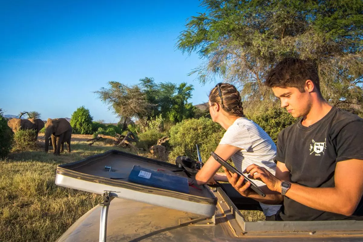 Two researchers studying elephants from their Jeep